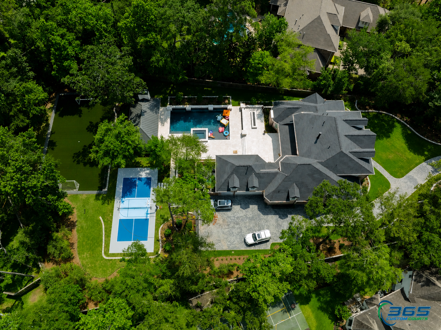 Wooded estate aerial with pickleball court, pool, and soccer field