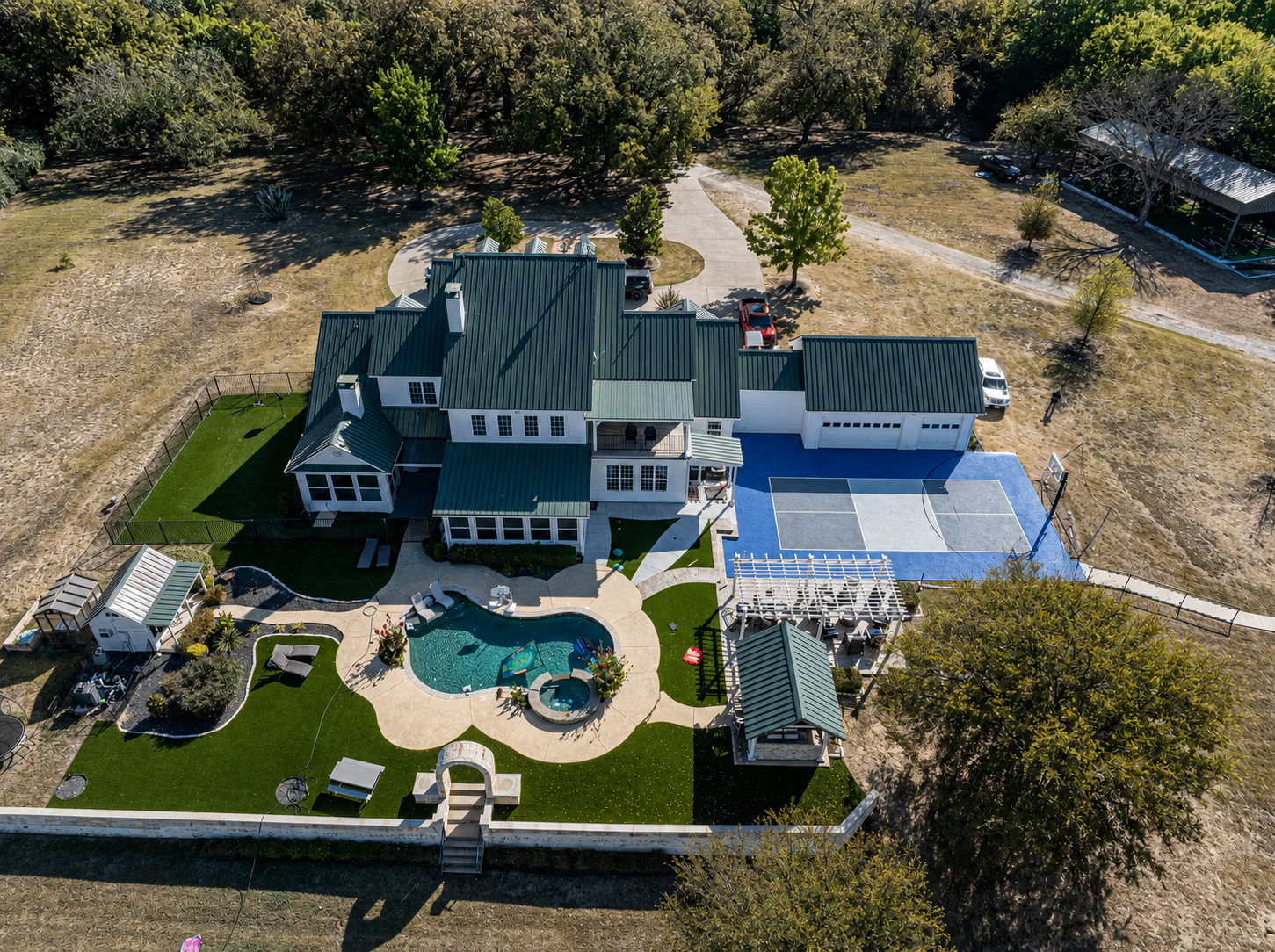 Green-roofed estate with pool, pickleball court, turf, and pergola