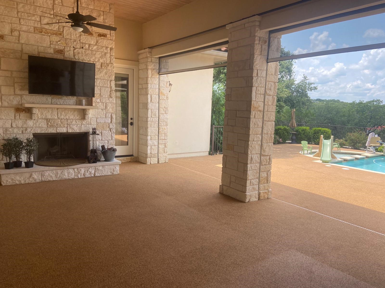 Covered patio with fireplace and rubber flooring by pool