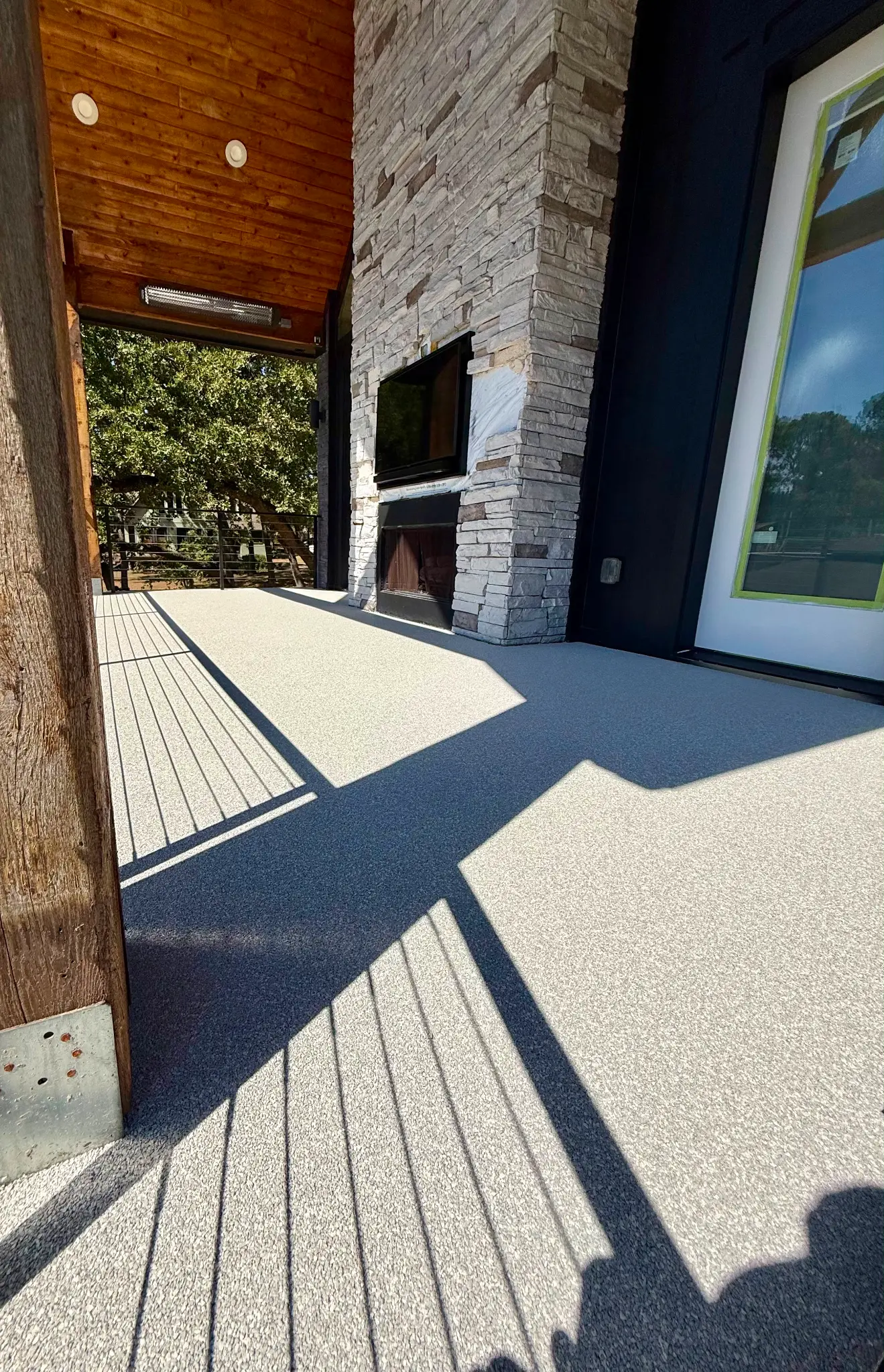 Covered patio with stone fireplace, rubber flooring, and cedar ceiling