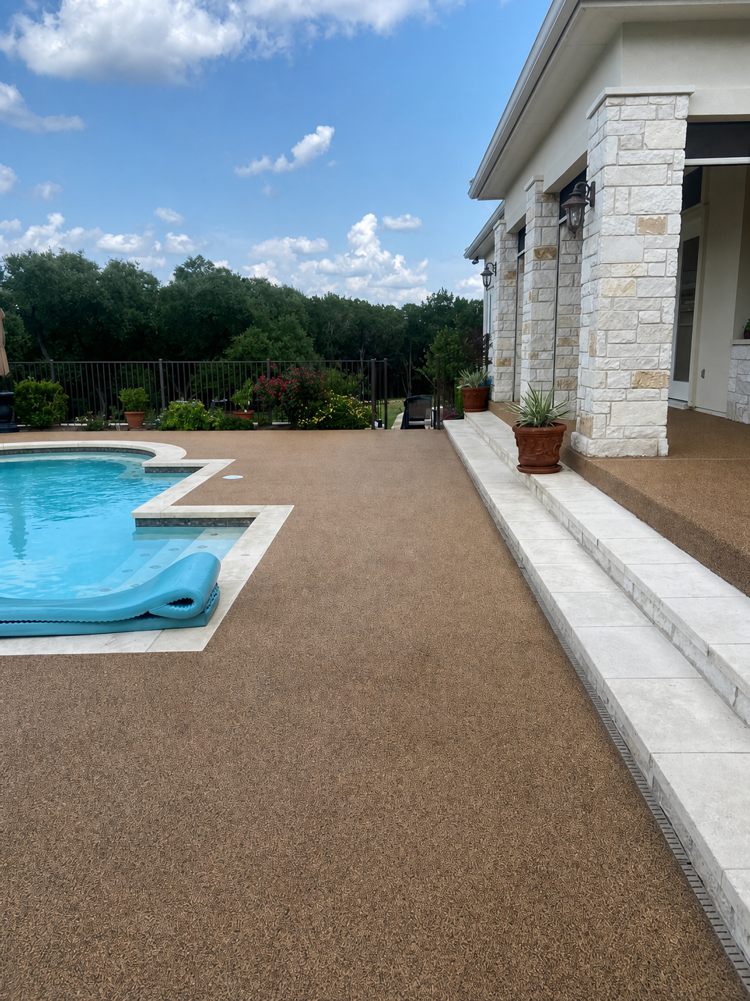 Rubber surfaced pool deck with stone house and blue pool