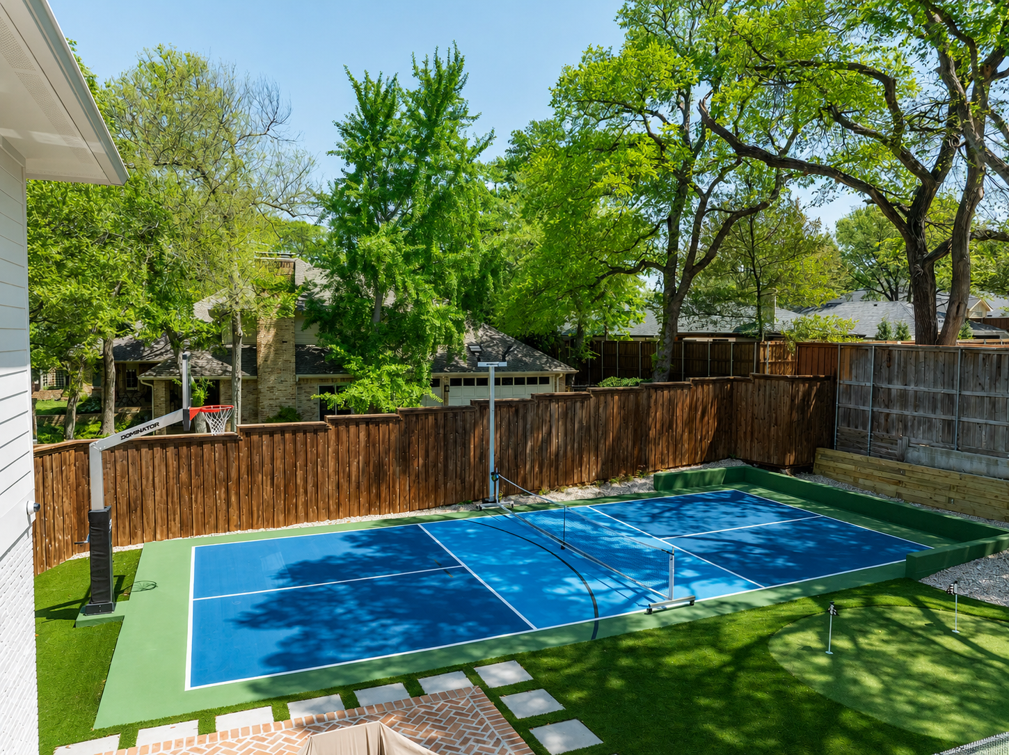 Backyard pickleball court with turf and fence