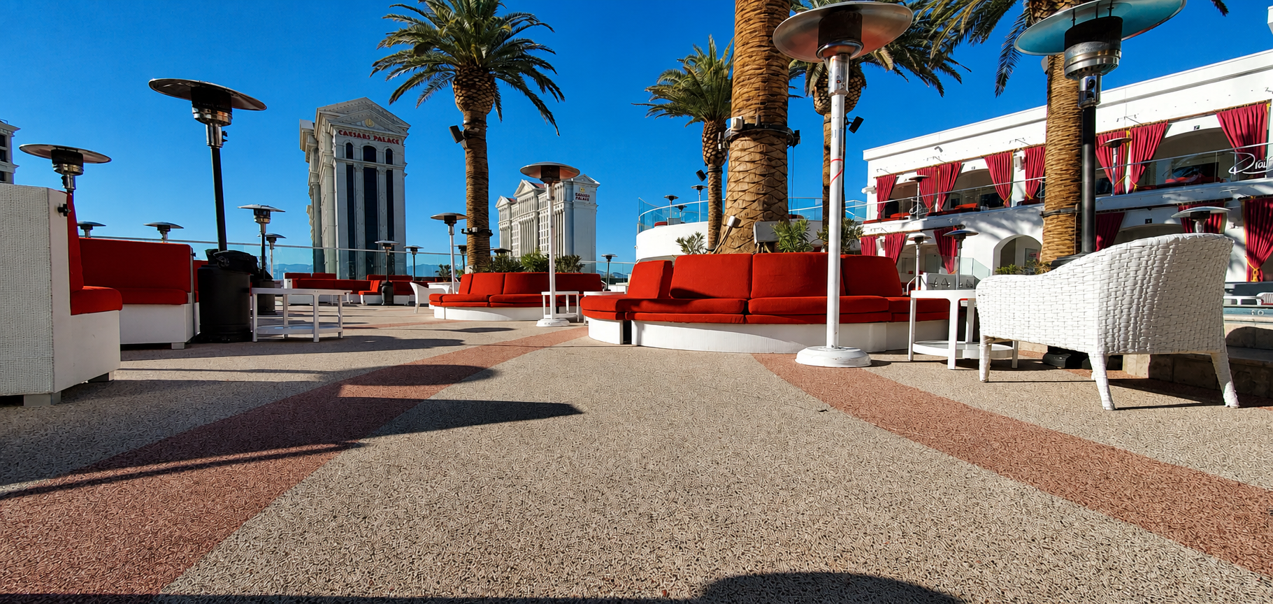 Drais Beachclub rooftop deck with red sofas and palm trees