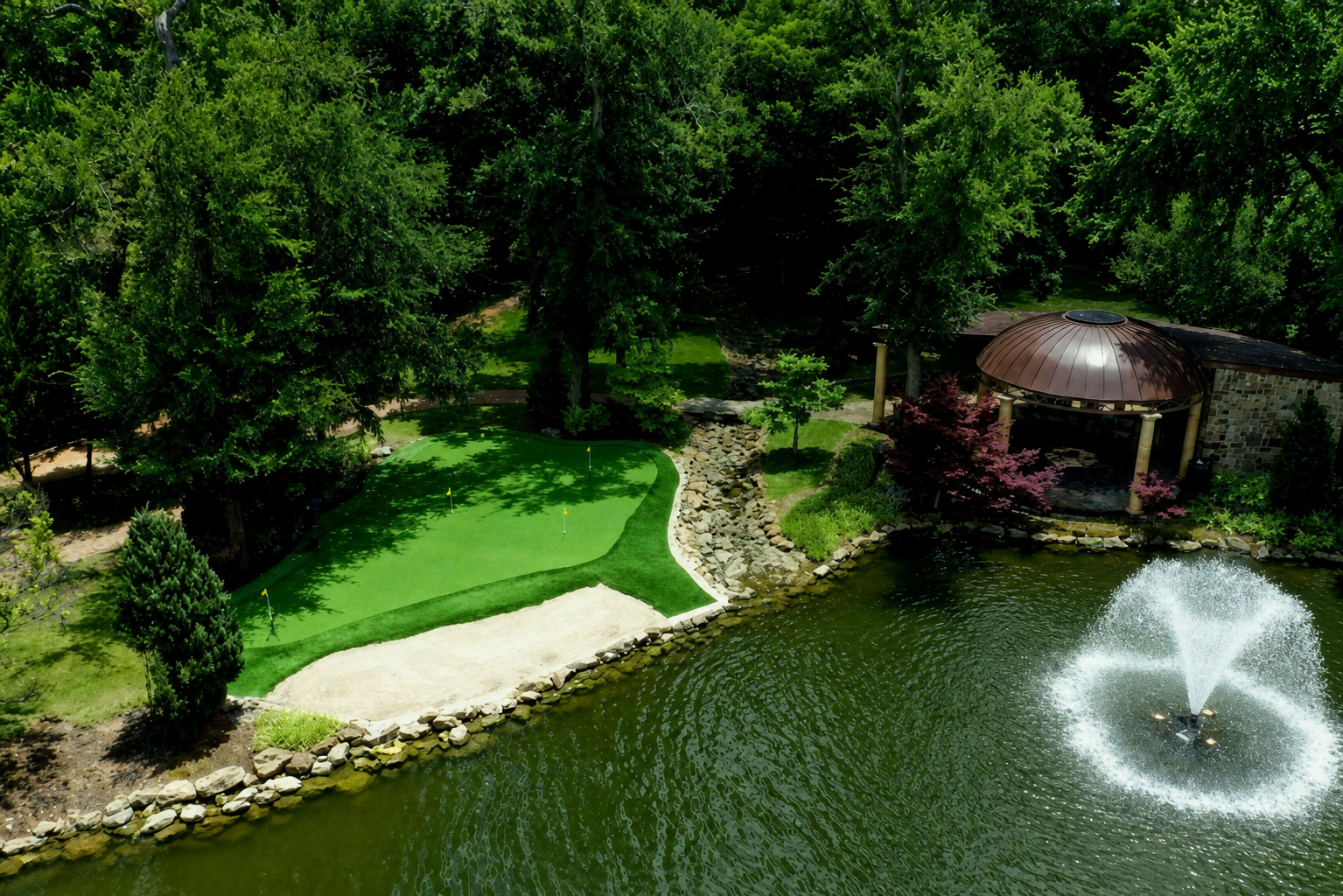 Putting green by pond with fountain and gazebo