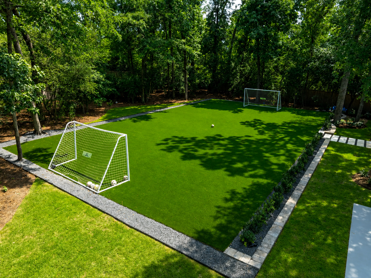 Backyard soccer field with artificial turf and goals surrounded by trees